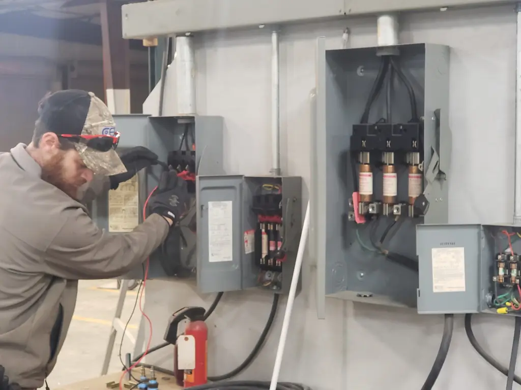 Peerless Electric technician in safety glasses working commercial grade fused disconnects