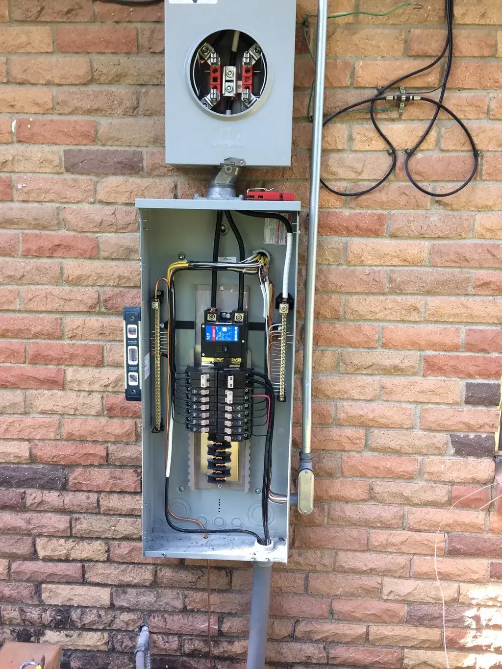 Finished exterior service panel and meter installed cleanly on a brick wall by Peerless Electric