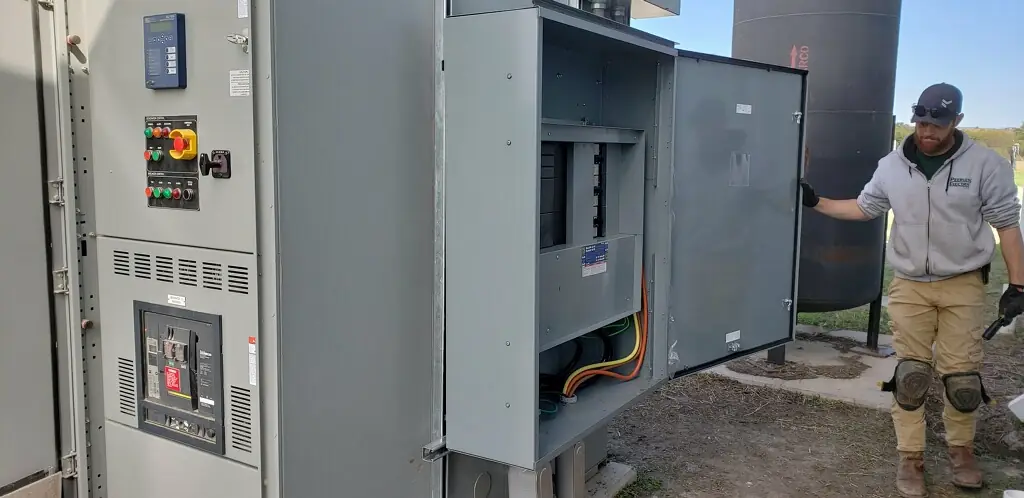 Peerless Electric technician at an outdoor commercial switchgear and generator enclosure